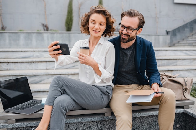 Attractive couple of man and woman sitting on stairs in urban city center