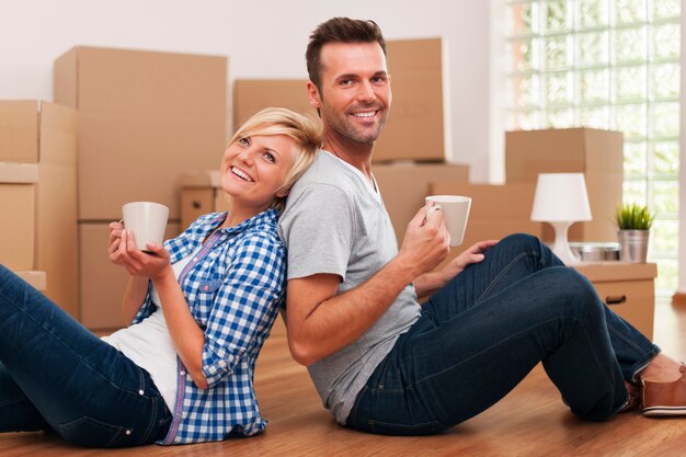 Attractive couple sitting on the floor at home with coffee cups