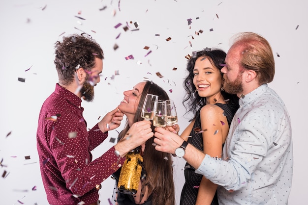 Attractive couples celebrating New Year while clinking glasses