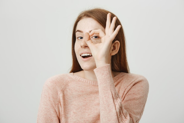 Free Photo attractive cute redhead girl showing okay gesture over eye