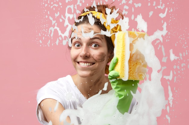 Free photo attractive cute young caucasian woman from cleaning service smiling broadly while tidying up in apartment, washing glass surface of window or shower stall, feeling excited and happy about her job