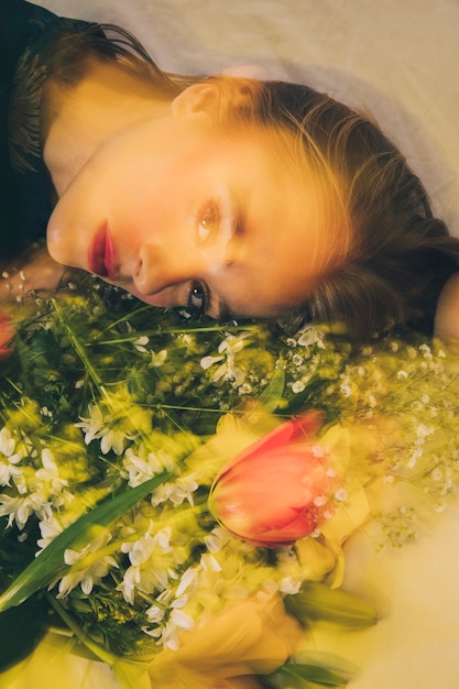 Attractive dreamy woman lying with bouquet of flowers