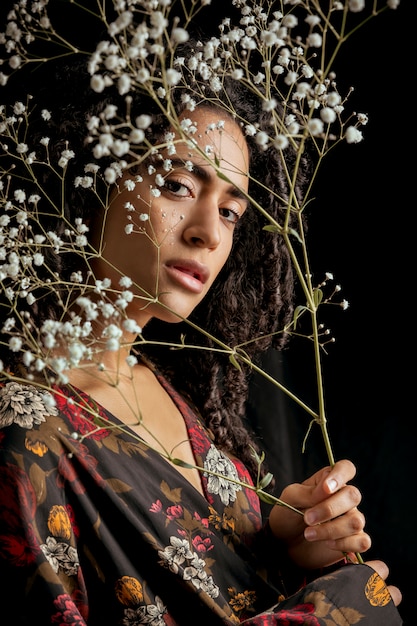 Free photo attractive ethnic charming woman with flower twigs in darkness