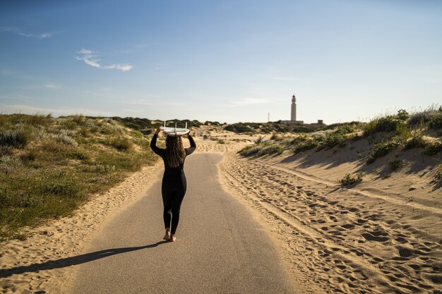 Attractive female carrying a surfboard above her head