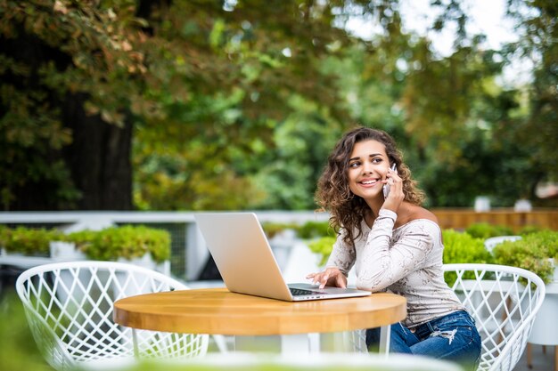 Attractive female freelancer hold smart phone while sitting in modern coffee shop