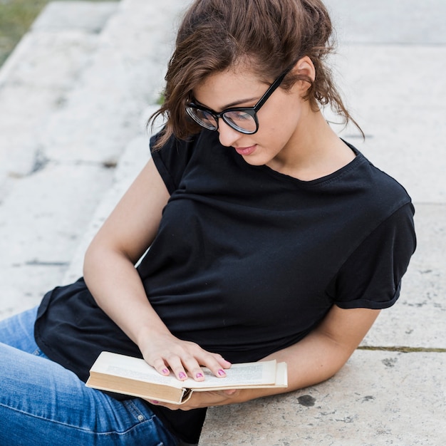 Free photo attractive female leaning on stairs with book