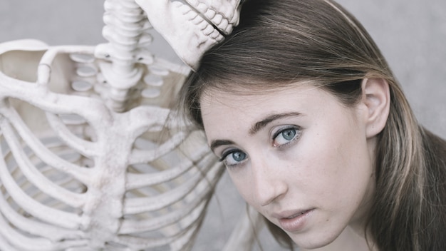 Free photo attractive female looking at camera next to decorative skeleton