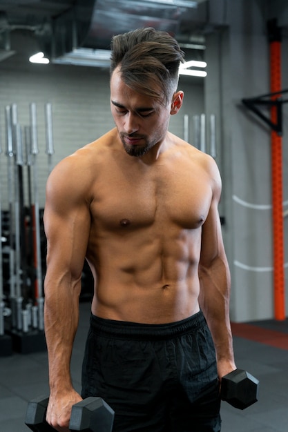 Attractive fit man working out indoors with dumbbells