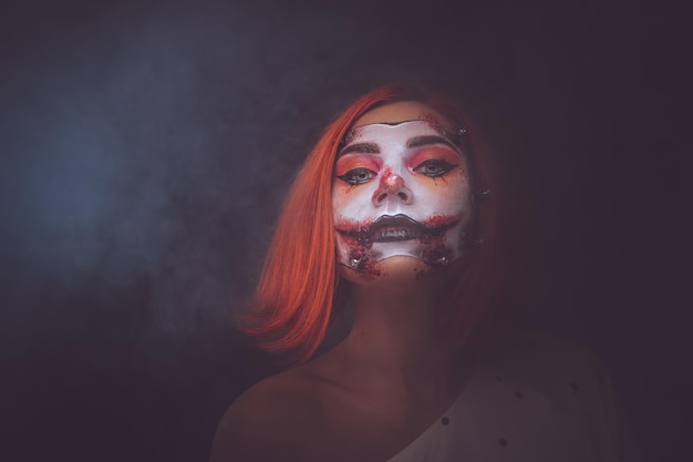 Free photo attractive girl is playing role of creepy dead doll in misty smoke.