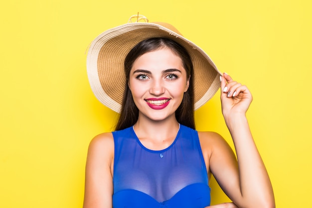 Attractive girl in a white bikini, hat, sunglasses, emotionally opened mouth on a yellow wall with a perfect body. Isolated. 