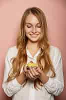 Free photo attractive girl in a white shirt is holding cupcakes