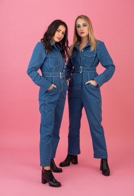 Free Photo attractive girls posing on pink background in denim overall fashion trend