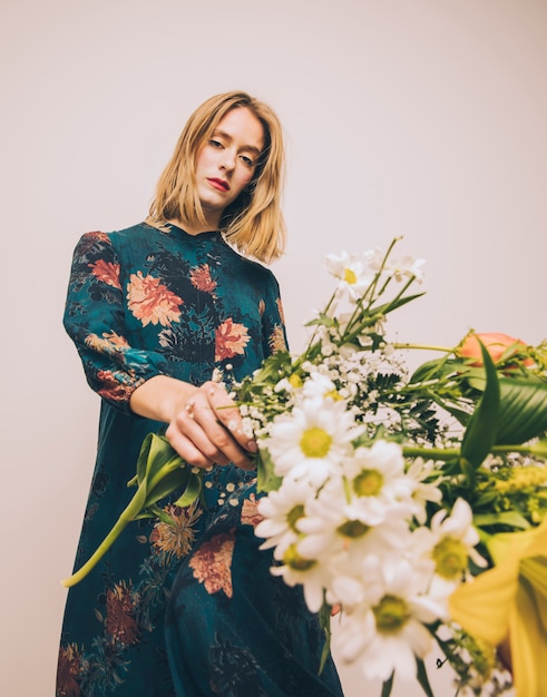 Attractive gorgeous woman in gown holding bouquet of fresh flowers