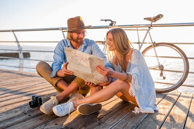 Attractive happy smiling couple traveling in summer by sea on bicycles