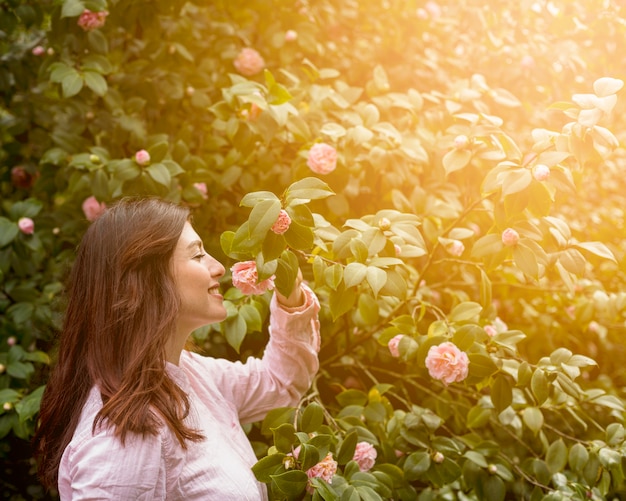 Attractive happy woman holding pink flower growing on green twig