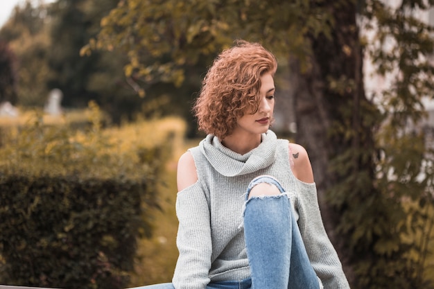 Free photo attractive lady on street wear sitting in park