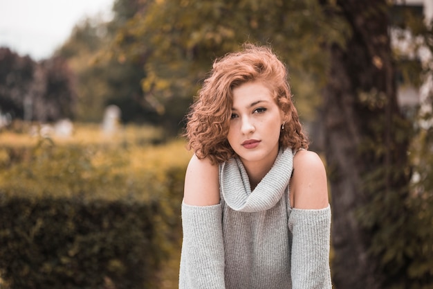 Free photo attractive lady with short curly hair in public garden