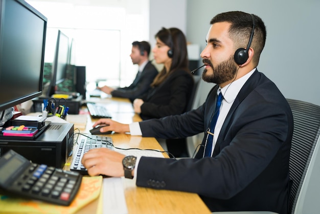 Free photo attractive latin executive offering customer service with a headset and offering tech support at a busy call center