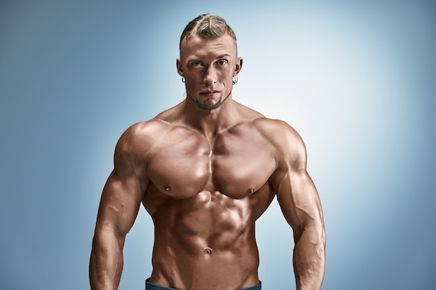 Free photo attractive male body builder on blue wall