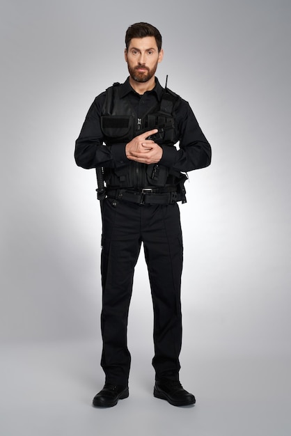 Free Photo attractive male cop with ammunition holding gun with both hands front view of bearded man in black