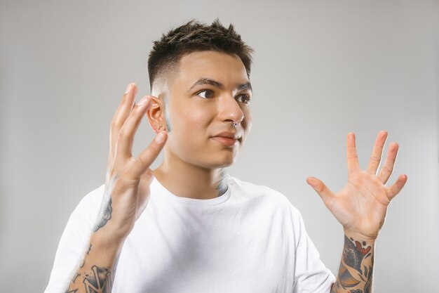 Attractive male half-length front portrait on gray studio backgroud. Young emotional surprised man.