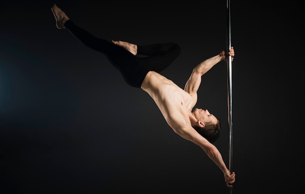 Free photo attractive male model performing a pole dance