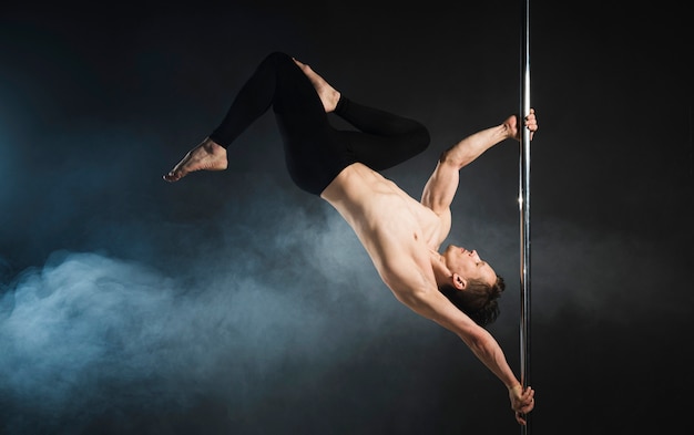 Attractive male model performing a pole dance