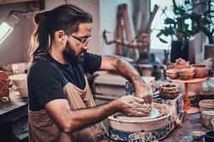 Free photo attractive man in glasses is working on his own clay project.