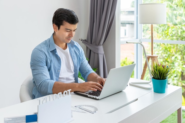 Attractive man is working at home using laptop computer notebook