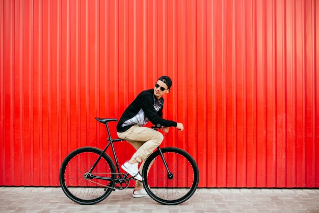 Free photo attractive man in sunglasses, sitting on professional bike, riding, looking back