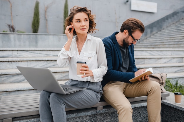 Attractive man and woman sitting on stairs in urban city center