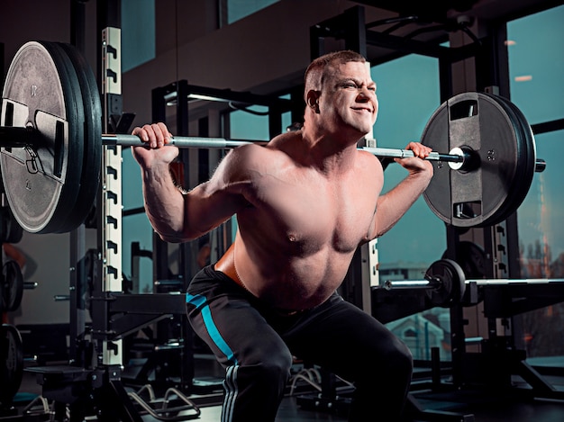 Attractive man works out with dumbbells in gym