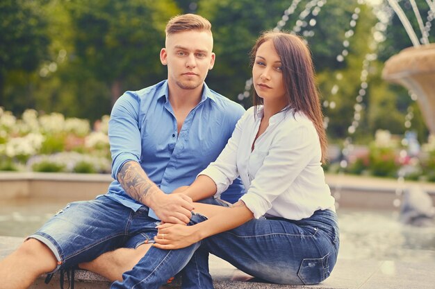 Attractive modern couple on a date is posing over city fountain.