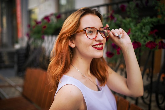 Free Photo attractive redhaired woman in eyeglasses posing at street of spring city