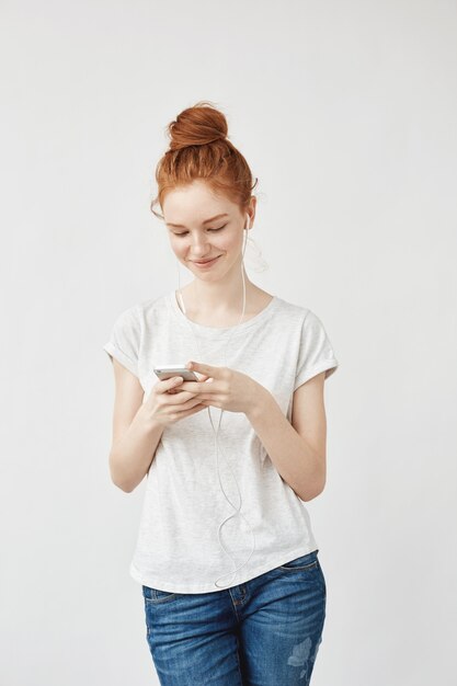 Attractive redhead woman with freckles smiling looking at phone.