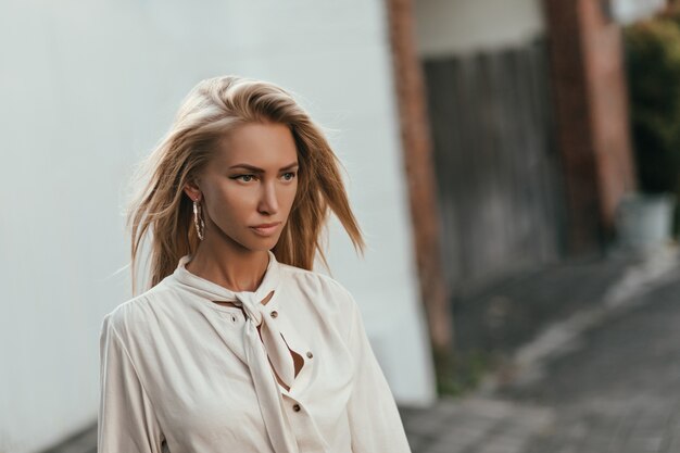 Attractive self-confident woman in light white blouse walks outside