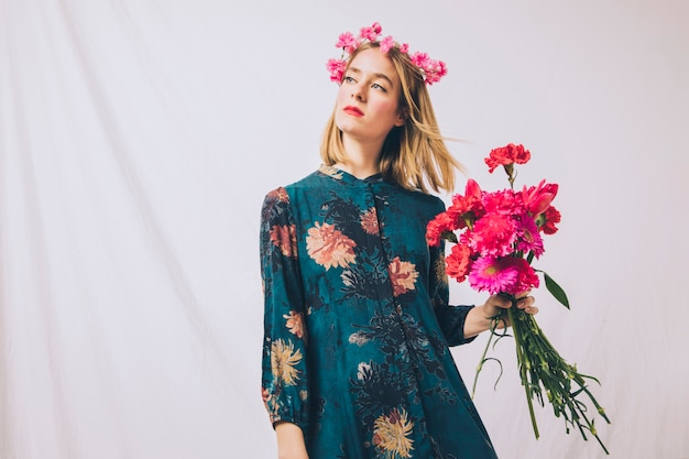 Attractive sensual woman with wreath on head and bouquet of flowers