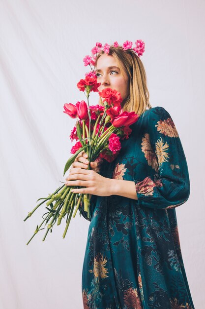 Attractive sensual woman with wreath on head smelling bouquet of flowers