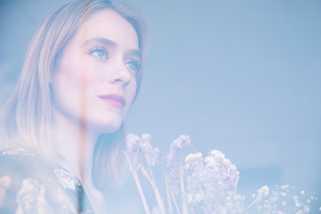 Free Photo attractive serious woman holding bouquet of dry plants behind window