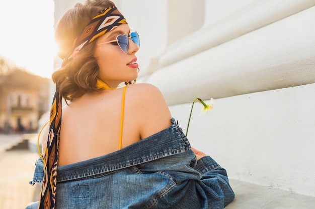 Free photo attractive sexy stylish woman in yellow stylish dress wearing denim jacket, trendy outfit, spring summer fashion trend, sunny, blue sunglasses, street fashion, hippie style, fashionable accessories