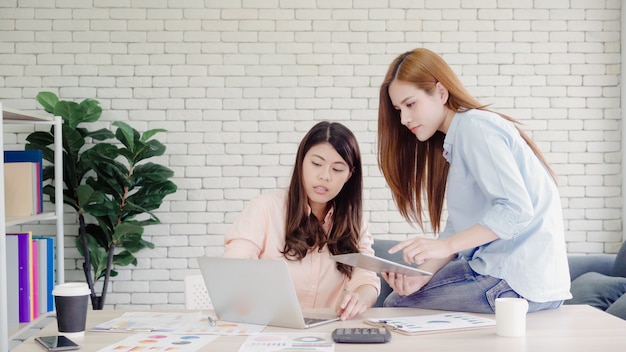 Attractive smart creative Asian business women in smart casual wear working on laptop while sitting 