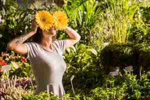 Free photo attractive smiling woman holding flowers near eyes