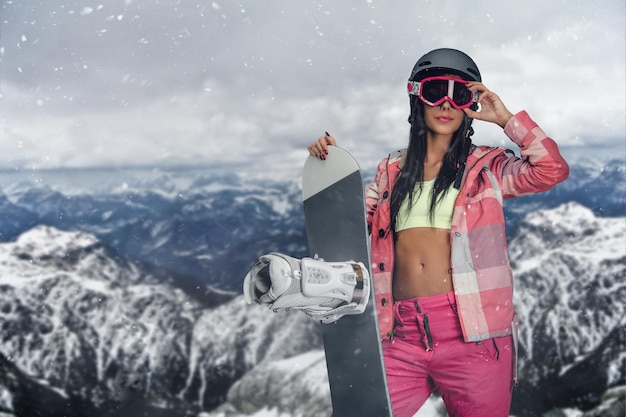 Free Photo the attractive sporty female holds snowboard in a photo session in high mountains.