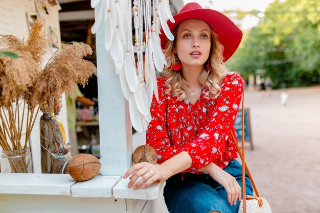 Attractive stylish blond smiling woman in straw red hat and blouse summer fashion outfit  cafe