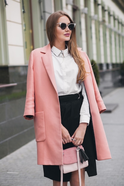 Free photo attractive stylish smiling rich woman walking city street in pink coat spring fashion trend holding purse, elegant style, wearing sunglasses