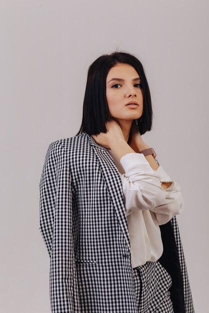 Attractive stylish young girl in business clothes posing on light background in studio. concept of stylish clothes and sophistication.