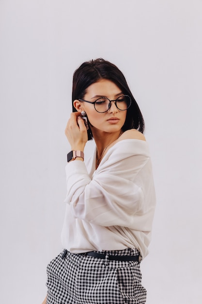 Attractive stylish young girl in business clothes posing on light background in studio. concept of stylish clothes and sophistication.