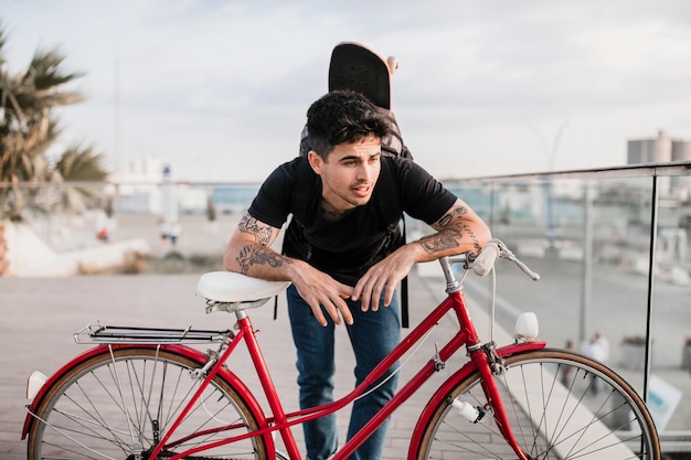 Attractive teenage boy leaning on red bicycle