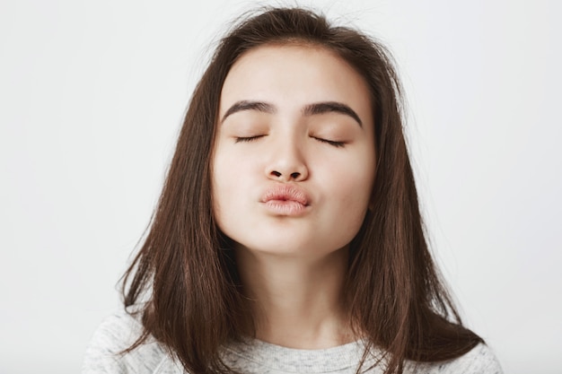 Free photo attractive tender european woman waiting for kiss with folded lips and closed eyes.