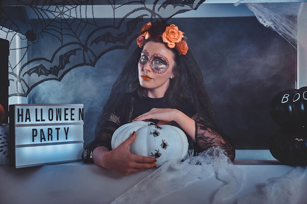 Free Photo attractive woman in dark dead bride role is posing for photographer with halloween decorations.